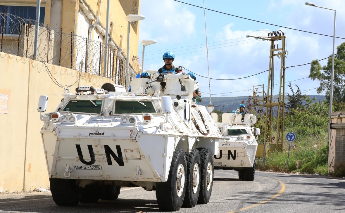 Israel strikes Lebanon after claiming it intercepted rockets that Hezbollah denies firing Soldiers in armoured trucks traverse a road next to a border wall.