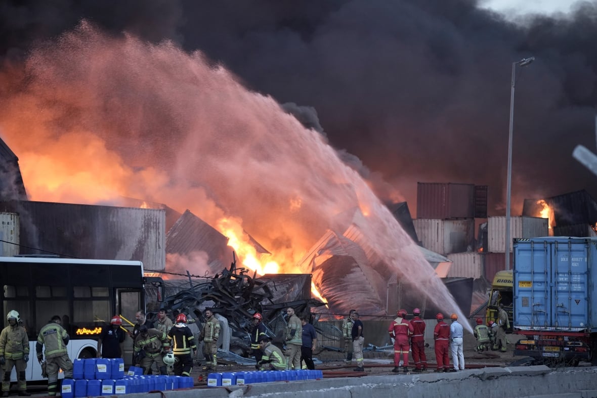 Firefighters try to extinguish a fire burning amid shipping containers.